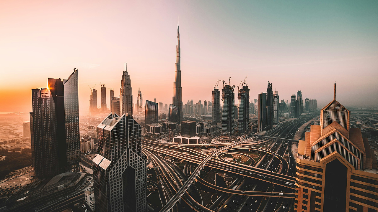 Panoramic view of Dubai’s skyline at sunset, featuring the Burj Khalifa surrounded by modern skyscrapers and intricate highway interchanges